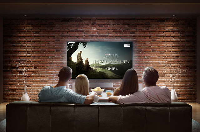 dwie pary siedzą na kanapie oglądając telewizję