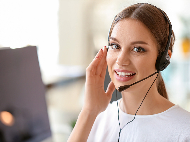 Uśmiechająca się kobieta trzyma kartki papieru. W&nbsp;tle widok wnętrza restauracji.