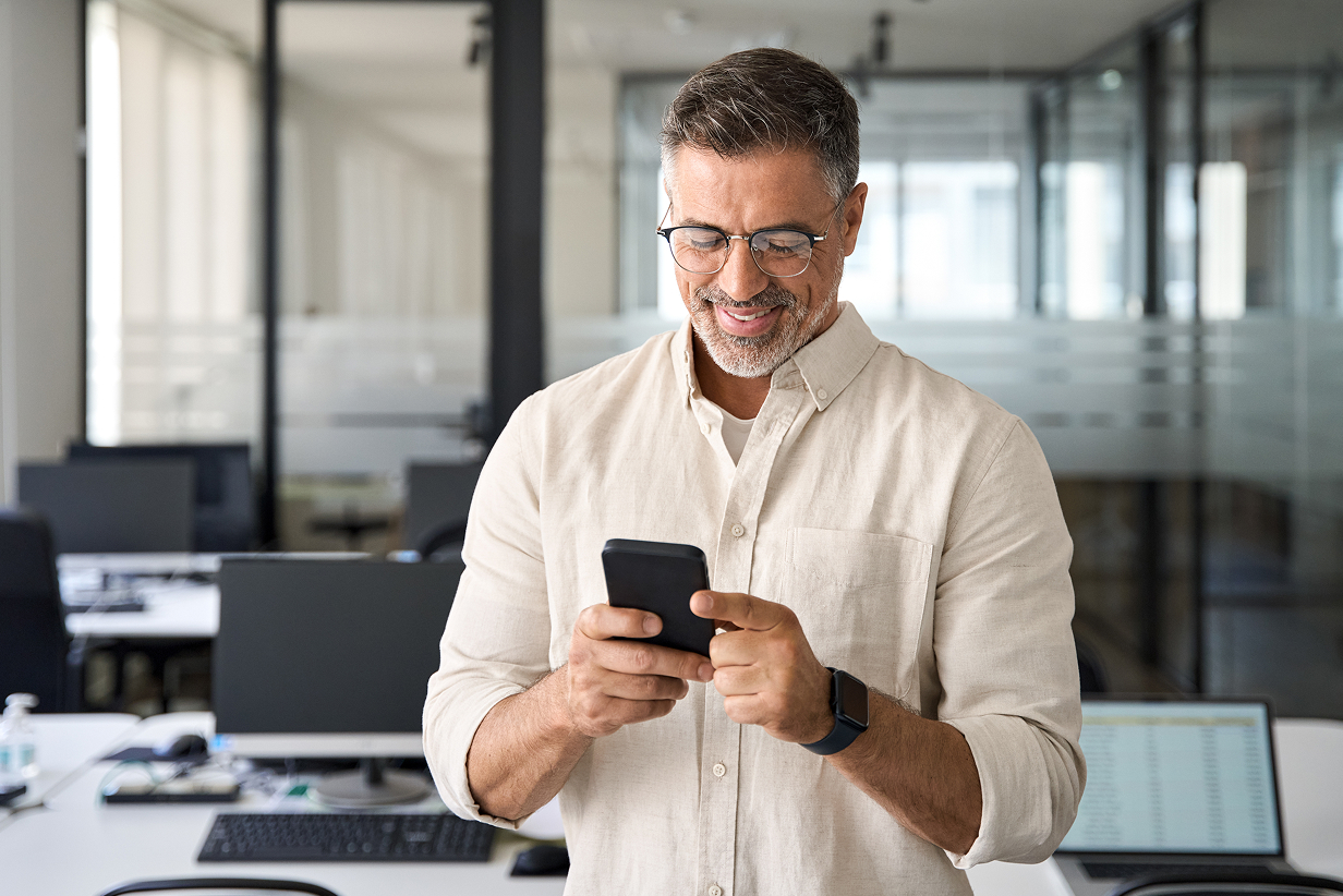 Zdjęcie przedstawia mężczyznę patrzącego w telefon