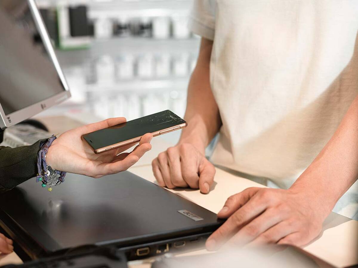 Kobieta trzyma w dłoni uszkodzony smartfon, pokazując go mężczyźnie