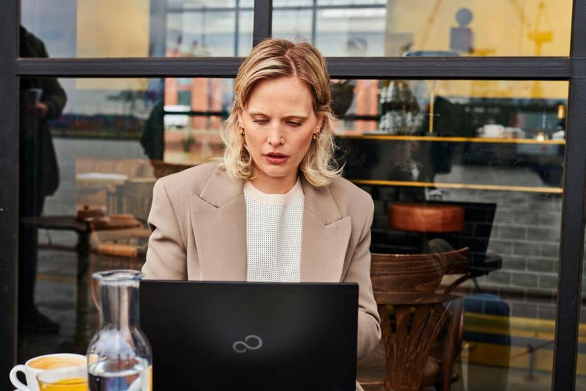 Kobieta pracuje na laptopie z mobilnym modemem, który zapewnia dostęp do internetu.