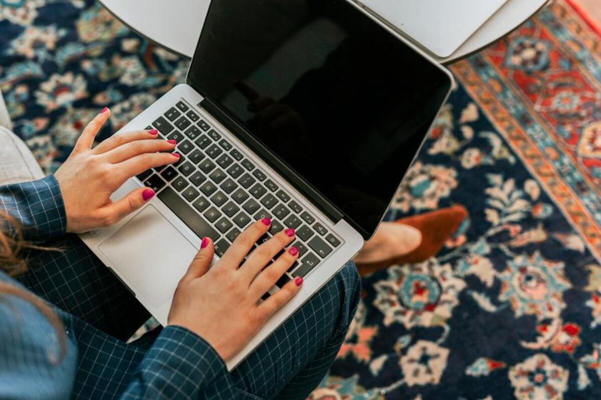 Kobieta trzyma na kolanach laptopa