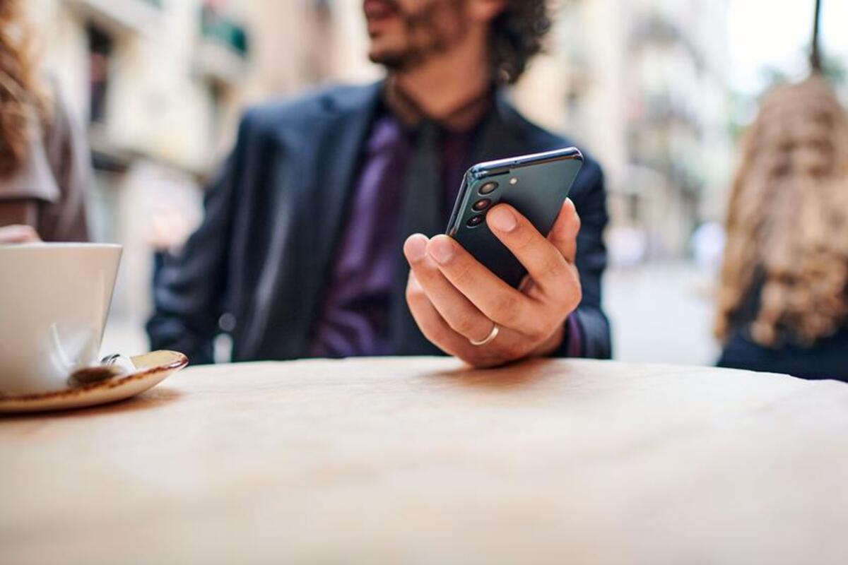 Mężczyzna w garniturze trzyma w dłoni telefon kupiony na firmę.