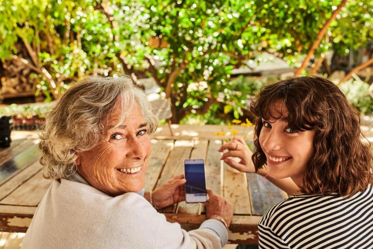 Wnuczka uczy babcię korzystać z telefonu dotykowego