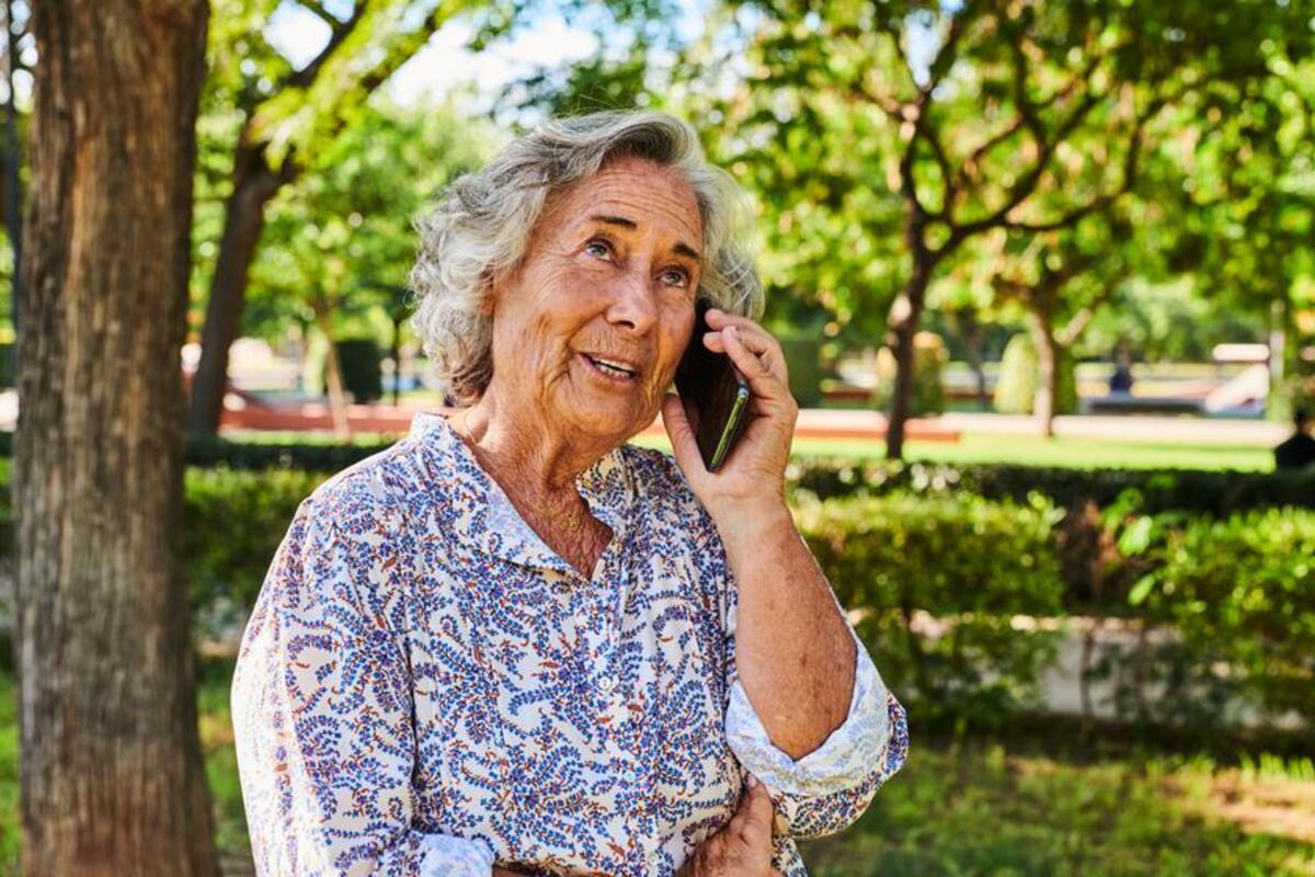 Starsza kobieta korzysta z telefonu dla seniora i rozmawia z bliskimi