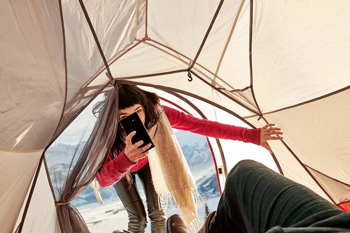 Młoda kobieta wchodzi do namiotu i robi zdjęcie telefonem